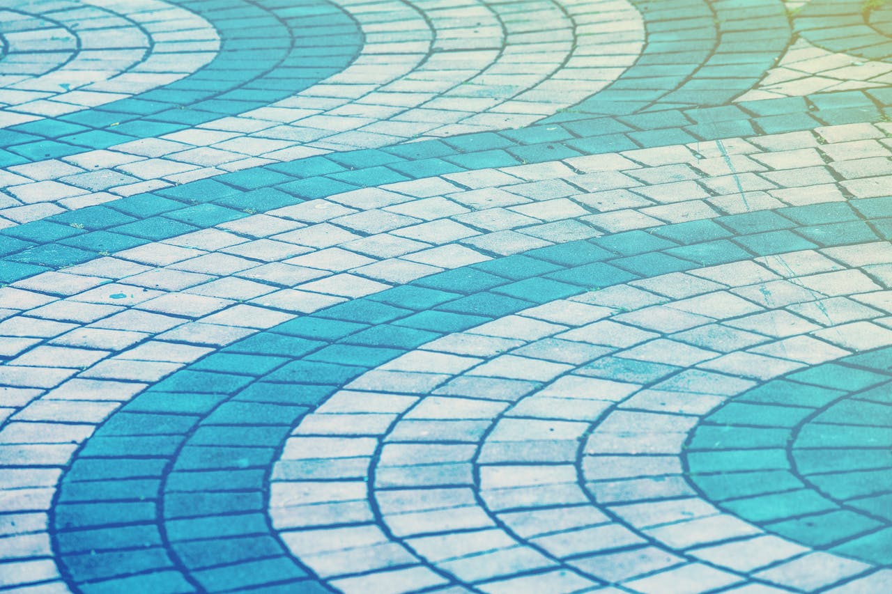 vision Curved blue and white paving tiles forming an abstract wave pattern on a walkway.