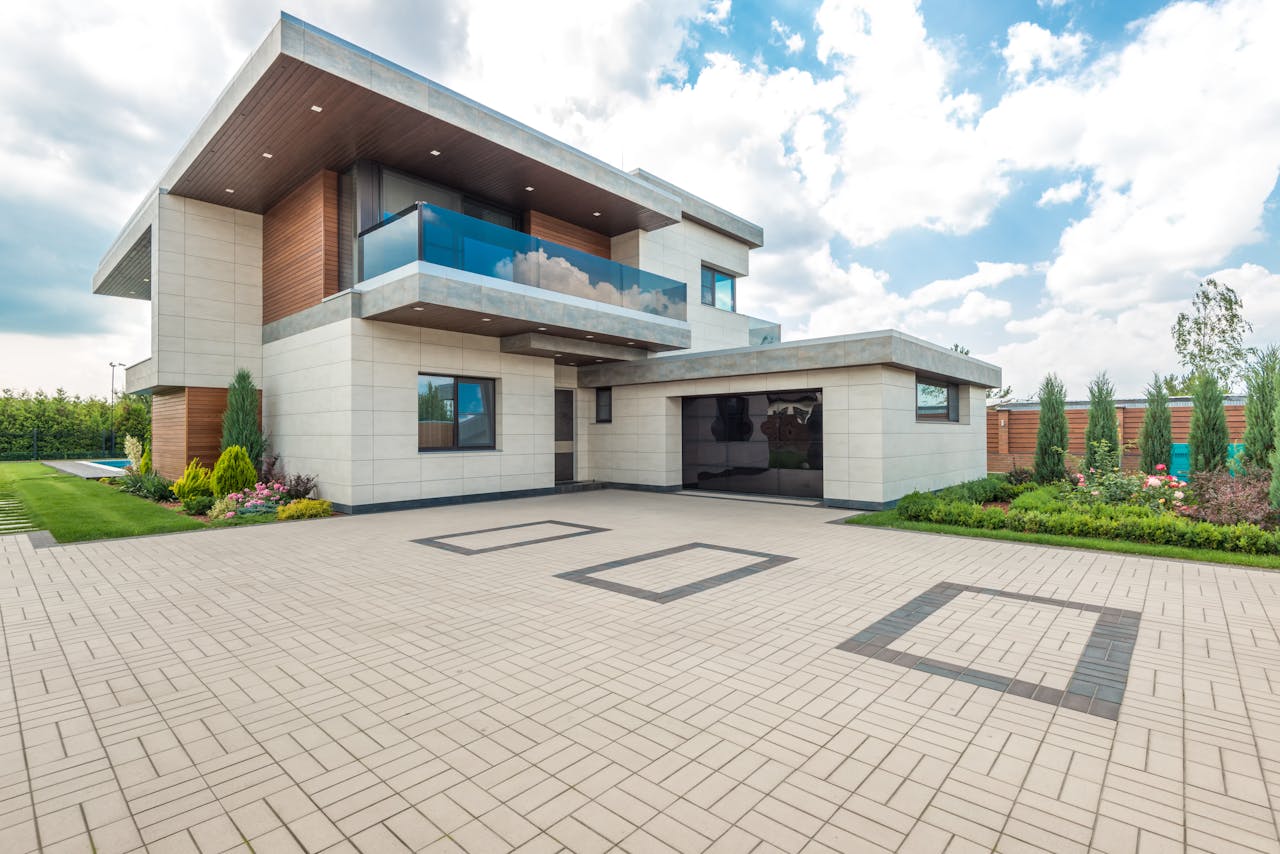 trusted-partner Elegant modern house exterior with lush greenery and ample driveway space.